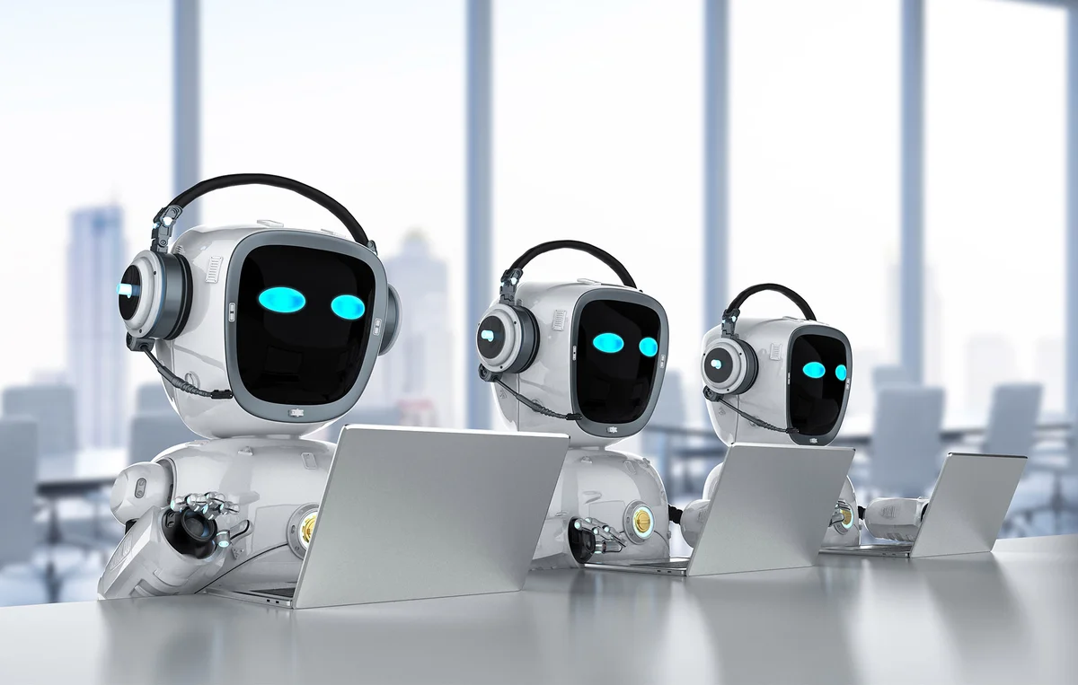 Three robots working side by side on laptops