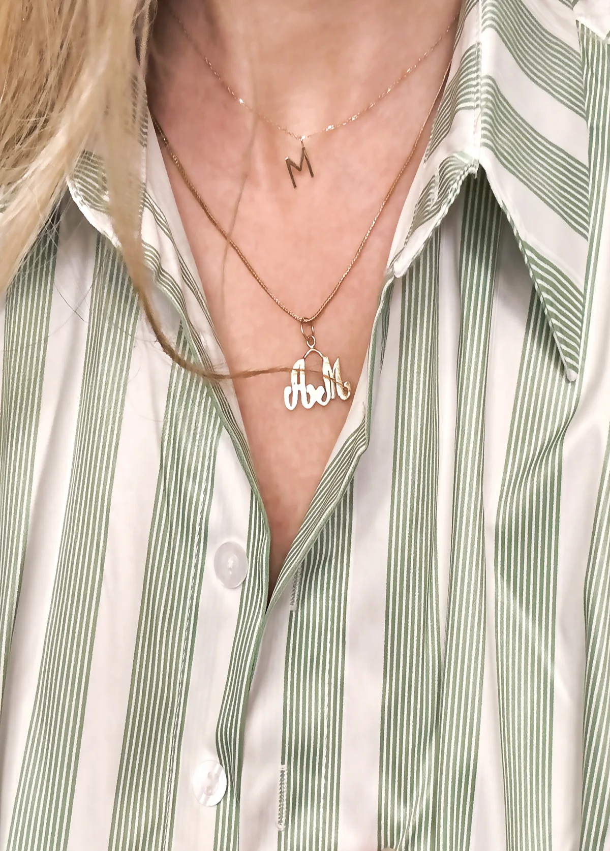 Gold initial necklaces worn together on bare skin
