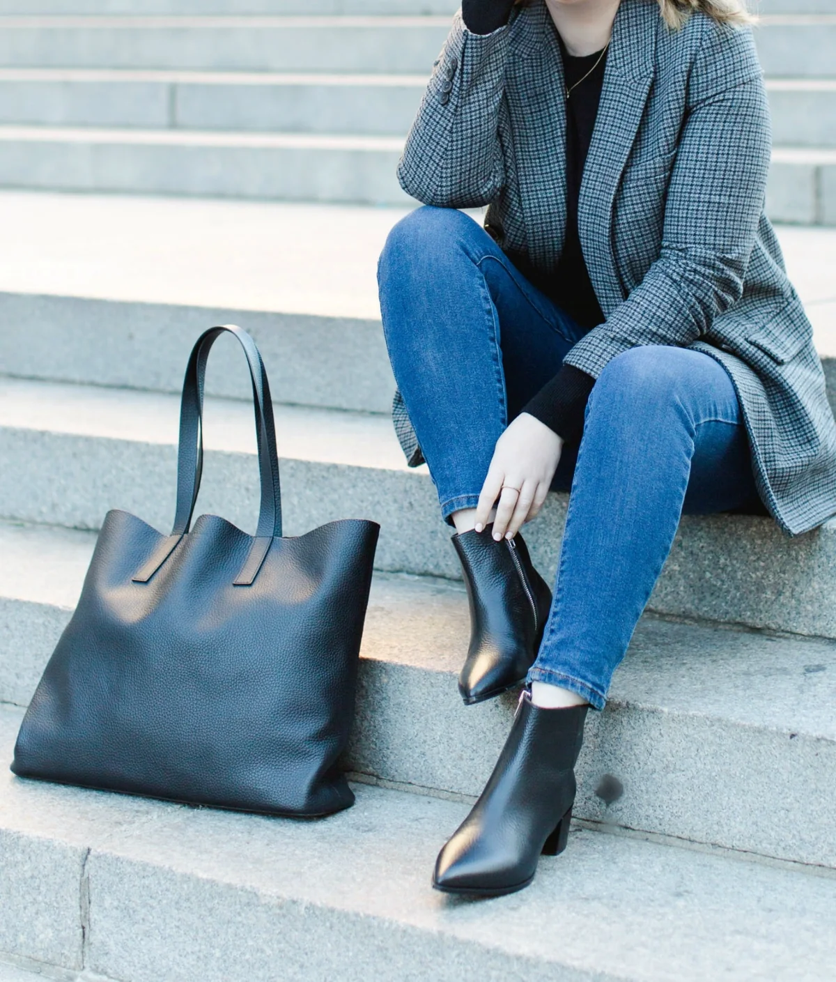 Woman in plaid blazer and jeans sitting on stone steps