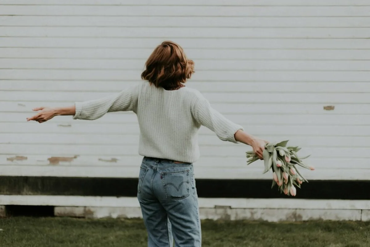 Same scene, woman with arms outstretched holding tulip bouquet