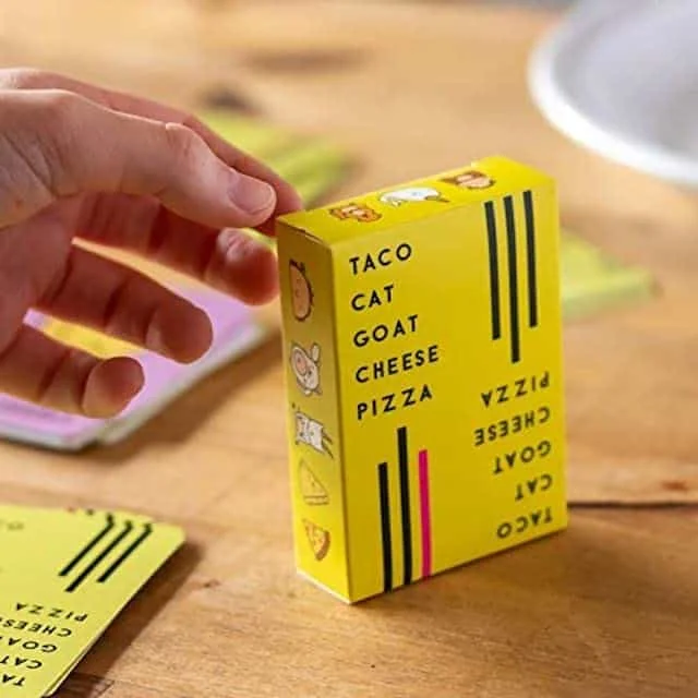 Hand holding a yellow Taco Cat Goat Cheese Pizza card game box